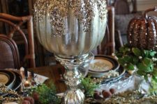 a metallic pumpkin with sequins and glitter on top on a vintage mercury glass stand as a glam centerpiece