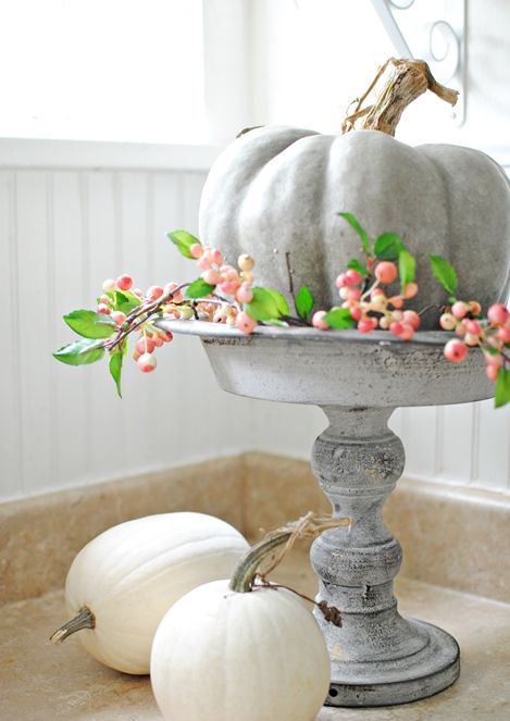 a milky painted pumpkin on a matching wooden stand, with berries looks and feels very farmhouse like