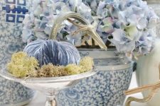 a mini blue velvet pumpkin with moss placed on a chic vintage stand brings elegance and chic to the space