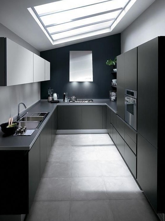 a minimalist black kitchen with sleek cabinets, grey stone countertops, white upper cabinets and a large skylight