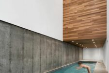 a minimalist house with a concrete wall and a stone deck, with a large pool and light over it – no furniture and no unnecessary details