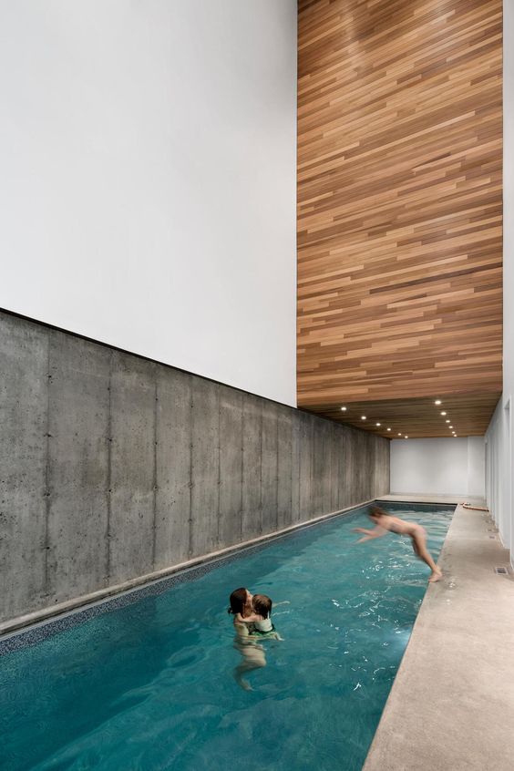 a minimalist house with a concrete wall and a stone deck, with a large pool and light over it   no furniture and no unnecessary details
