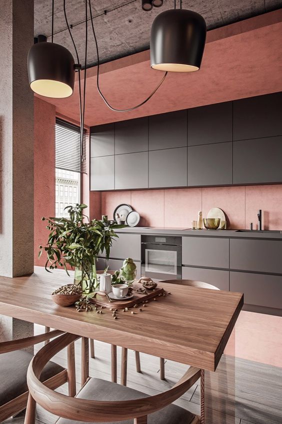 a minimalist kitchen in pink, with sleek graphite grey cabinetry, a concrete ceiling and a small dining space