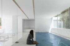 a minimalist white pool house with a long and narrow pool, a stone deck and views of outdoors is a lovely idea