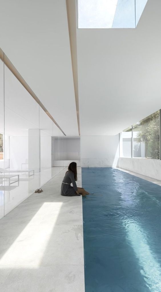 a minimalist white pool house with a long and narrow pool, a stone deck and views of outdoors is a lovely idea