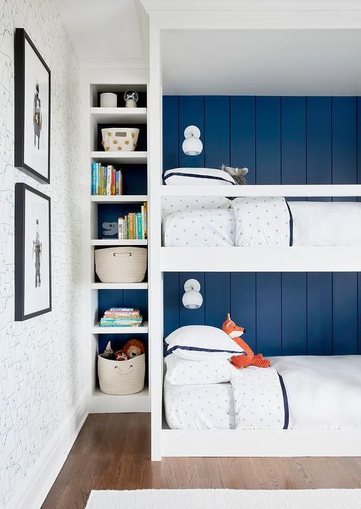 a modern and stylish kids' room with navy shiplap walls, a white bunk bed built-in, built-in shelves, baskets, toys and artwork welcomes in