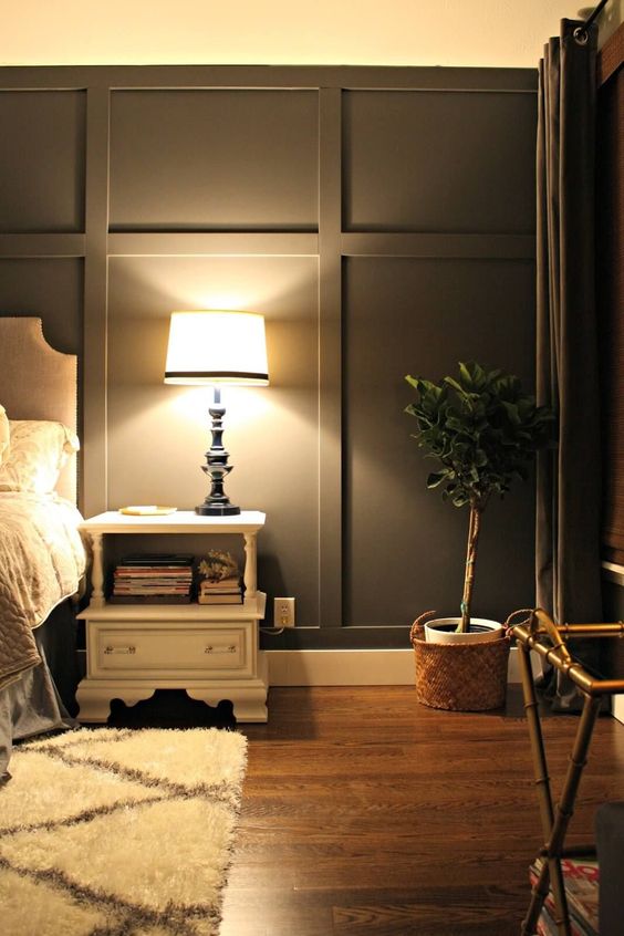 a modern farmhouse bedroom with grey walls and molding, with chic furniture, a potted plant and a printed rug is cool