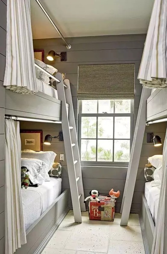 a modern grey kids' room with built-in bunk beds, neutral and grey bedding, ladders and striped curtains plus black sconces
