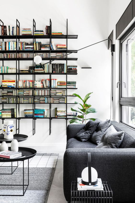a modern home library with a floating black bookshelf unit and some contemporary furniture