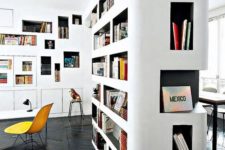 a modern home library with a white and black bookcase with niches that doubles as a space divider