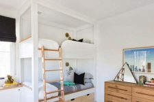 a modern kids’ room with built-in bunk beds, with neutral bedding, a stained dresser, a triangle mirror, shelves and toys here and there