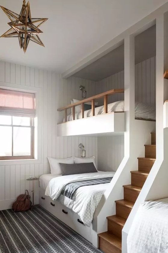 a modern kids' room with white shiplap walls, built-in bunk beds with printed bedding, a gold star-shaped pendant lamp and a ladder
