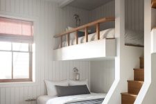 a modern kids’ room with white shiplap walls, built-in bunk beds with printed bedding, a gold star-shaped pendant lamp and a ladder