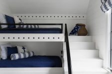 a modern nautical kids’ room with built-in bunk beds, navy and white bedding, a striped rug and some pretty decor