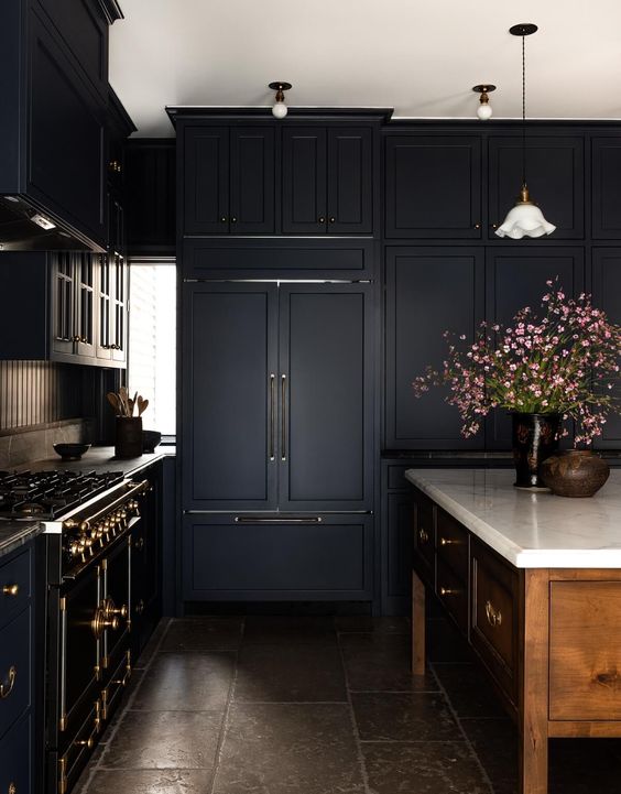 a moody kitchen with black shaker cabinets, a rich-stained kitchen island, a vintage-style black cooker and touches of brass