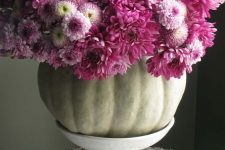 a natural pumpkin with lots of purple blooms on a white stand is a chic and bright rustic centerpiece
