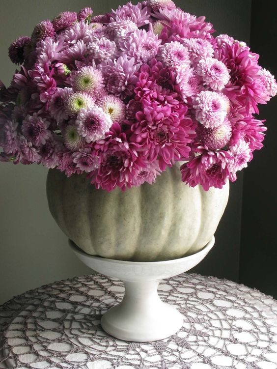 a natural pumpkin with lots of purple blooms on a white stand is a chic and bright rustic centerpiece