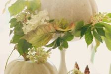 a natural pumpkins with fall foliage and white blooms, with white pumpkins and pears makes up a cool fall centerpiece