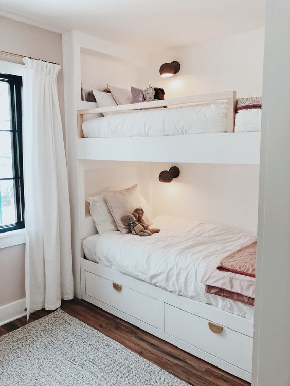 a neutral and welcoming kids' room with white built-in bunk beds, neutral bedding, sconces and neutral textiles is a very cozy space to be in