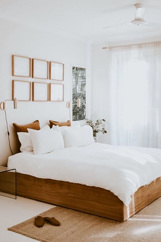a neutral bedroom with a gallery wall, a wooden bed with neutral bedding, the spac elooks larger thanks to the colors