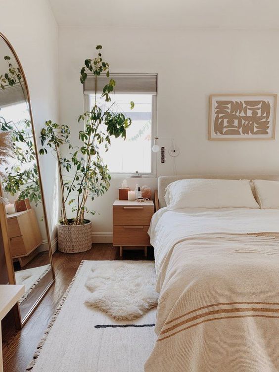 a neutral color scheme plus a large floor mirror make the bedroom look big and very welcoming