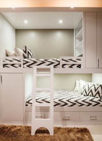 a neutral kids' room with built-in bunk beds, printed bedding, built-in shelves, a ladder and drawers for storage