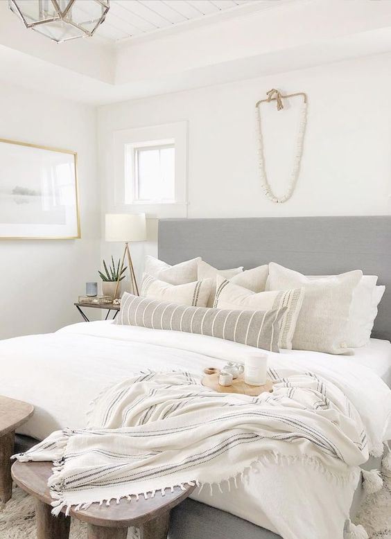 a neutral small bedroom looks larger cause of an extended headboard, a neutral color scheme and enough light