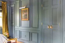 a pastel blue room with molding on the walls and doors, with gold and mustard touches and a pretty mauve chair