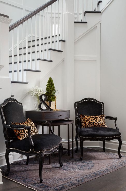 a refined nook with antique black chairs, leopard pillows, a side table and some greenery and blooms