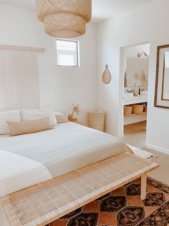 a small bedroom looks larger thanks to thr neutral color scheme and wicker and woven pieces that are added for decor