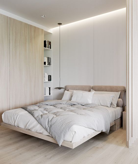 a small bedroom made larger with a neutral color scheme, with built-in lights and floor to ceiling shelves