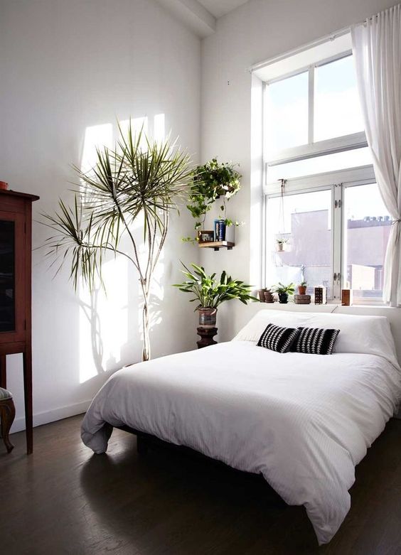 a small bedroom with a window over the bed that fills the whole space with natural light, white walls help with that, too