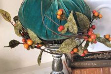 a teal velvet pumpkin, fabric leaves and berries on a shabby chic wooden stand is a bright fall decoration