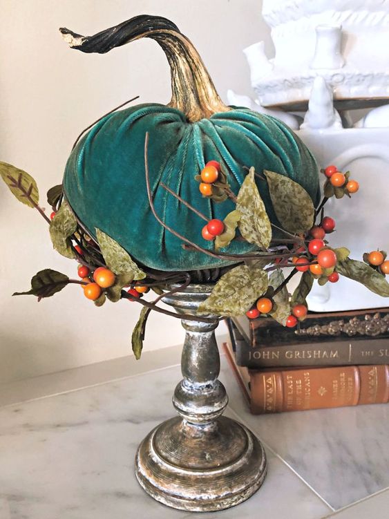 a teal velvet pumpkin, fabric leaves and berries on a shabby chic wooden stand is a bright fall decoration