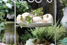 a tiered stand with natural pumpkins and greenery is a perfect farmhouse decoration for the fall