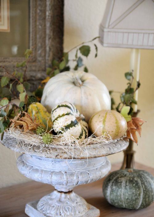 a vintage urn with hay, natural pumpkins and gourds and leaves is a cool centerpiece for the fall