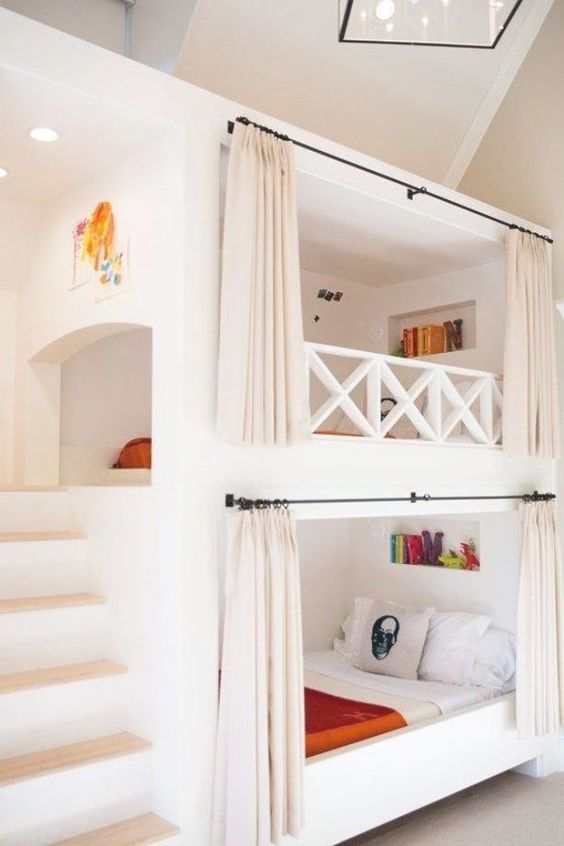 a white kids' room with built-in bunk beds, shelves, bright bedding, built-in lights and lamps is a cool and welcoming space