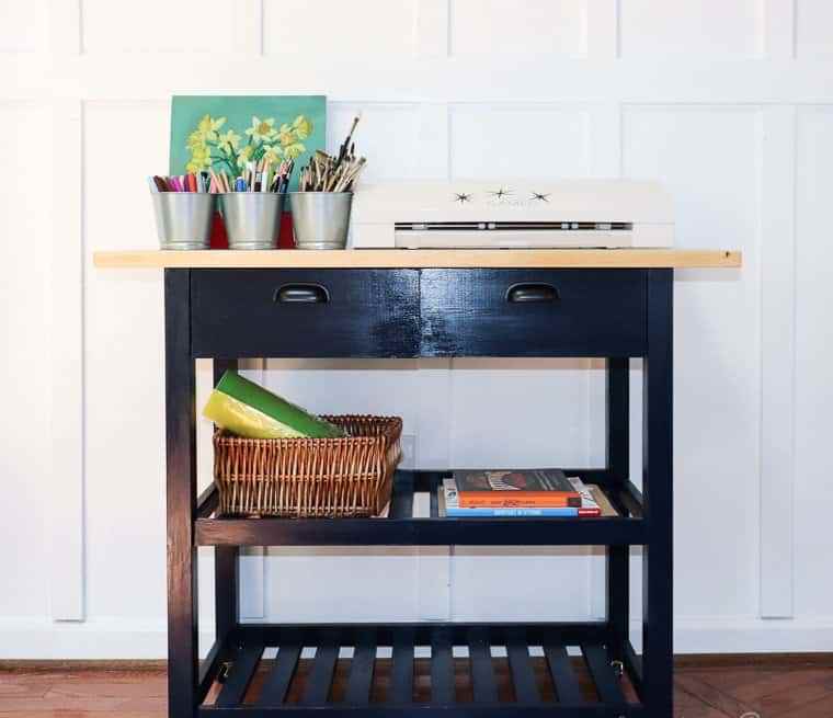 an IKEA Forhoja cart hacked with black paint and with a wooden countertop used as a craft or art cart at home