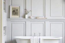 an airy bathroom with molding on the walls, a built-in shelf, a refined clawfoot tub is a very calming and soothing space