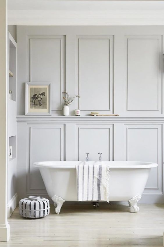 an airy bathroom with molding on the walls, a built-in shelf, a refined clawfoot tub is a very calming and soothing space