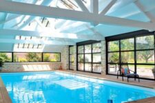 an attic pool house with a large pool, a wooden deck, glazed walls and an additional window plus skylights is cool