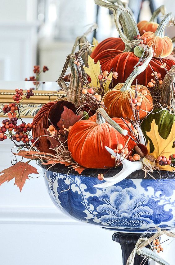 lots of bright velvet pumpkins, berries, antlers and faux leaves in a blue handpainted bowl for a bold centerpiece