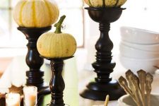 natural mini pumpkins on black wooden stands, with candles and fall leaves for a natural vintage centerpiece