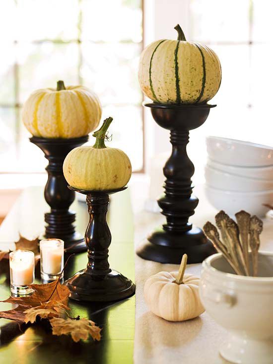 natural mini pumpkins on black wooden stands, with candles and fall leaves for a natural vintage centerpiece