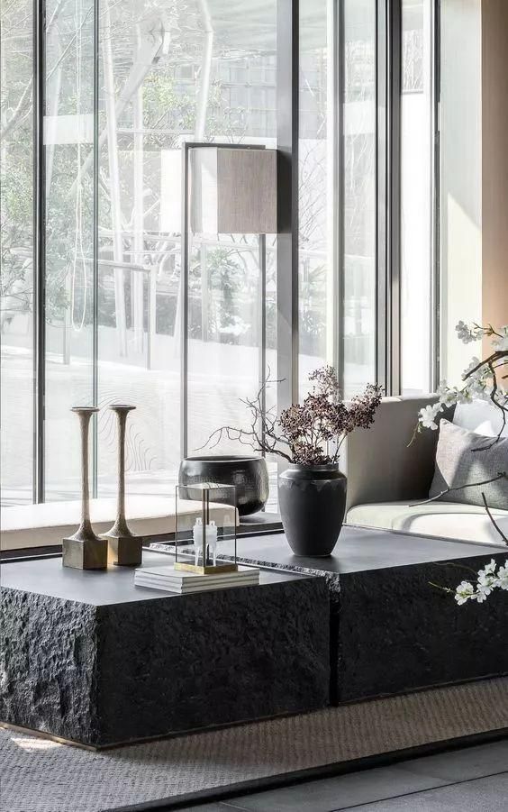 rough black coffee tables with candle holders, a black vase with dried herbs and a candle lantern and books