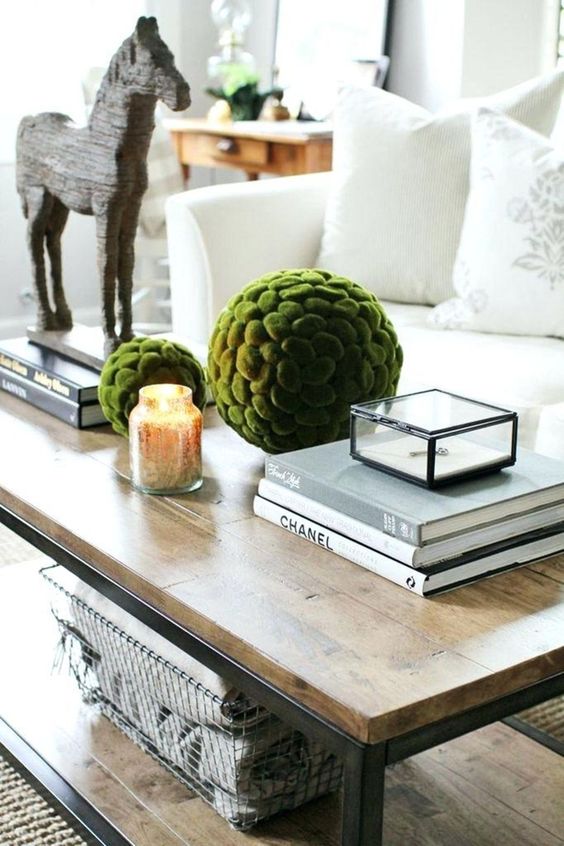 stacks of books, a candle in a mercury jar, large moss balls and a horse figurine