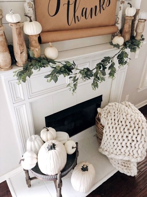 white pumpkins on vintage wooden stands and a dark wooden stand with lots of white pumpkins by the fireplace