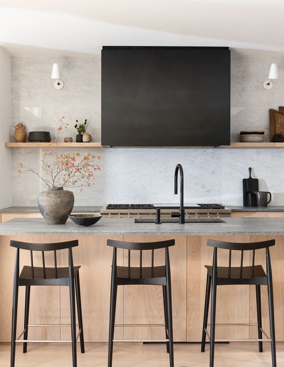 a beautiful contemporary kitchen with stained cabinets, a stained kitchen island with stone countertops, catchy black stools and fixtures