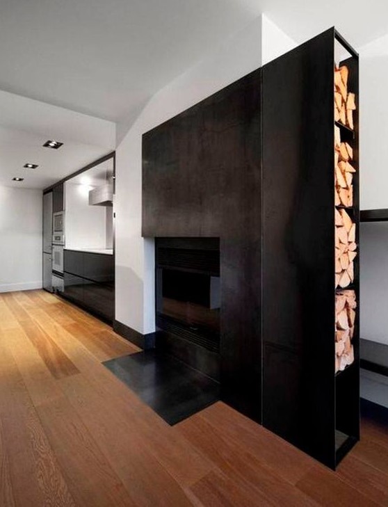 a blackened metal fireplace with a large firewood storage on its side is a bold and cool decor feature