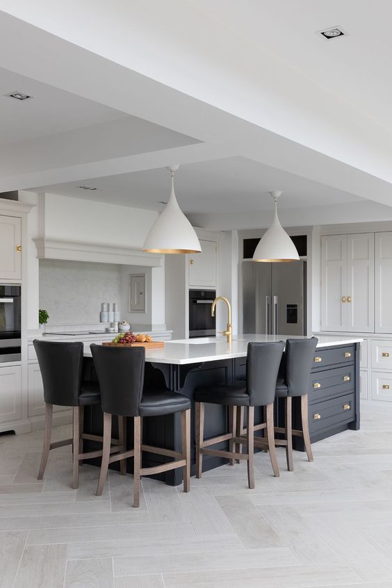 a bold contrasting kitchen with white shaker style cabinets, a black kitchen island with storage and black leather stools and pendant lamps